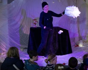 A person with a fluffy cloud and a group of children watching the performance